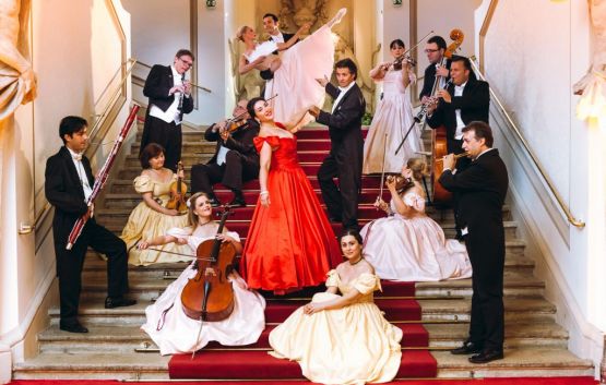 Orchester und Tänzer in historischen Kostümen auf einer Treppe.