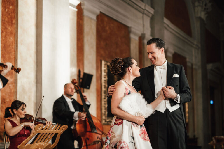 Paar beim Tanz in einem stilvollen Saal, begleitet von einem Orchester