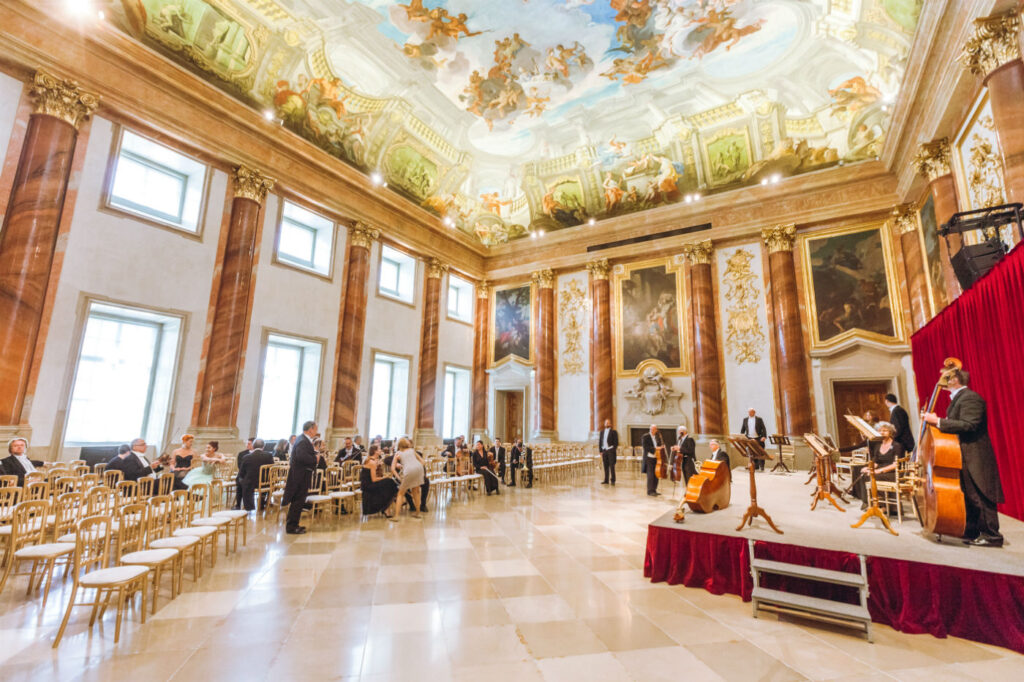 Herkulessaal im Palais Liechtenstein mit aufwendiger Deckenmalerei und Musikern vor einem Konzert.