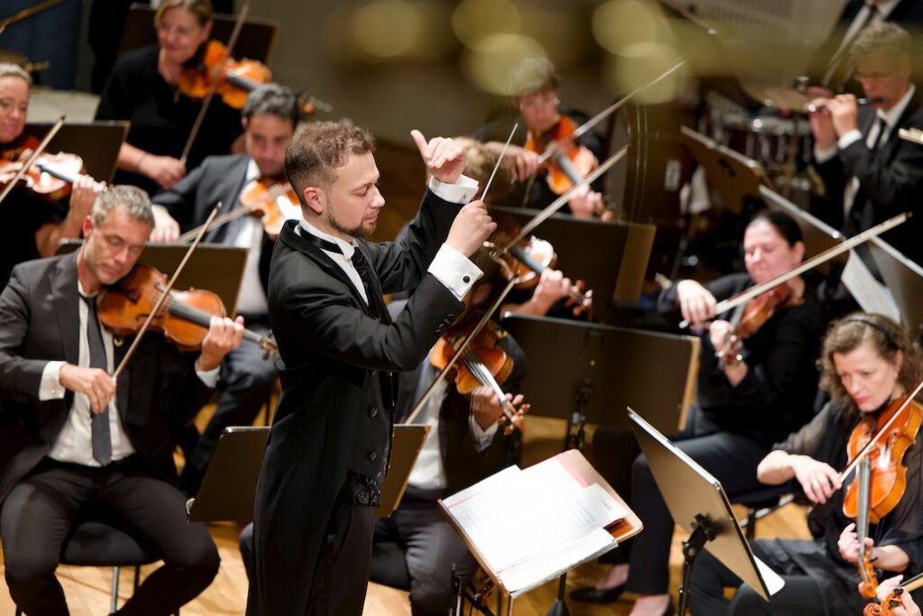 Dirigent führt ein Orchester mit Streichern während eines Konzerts.